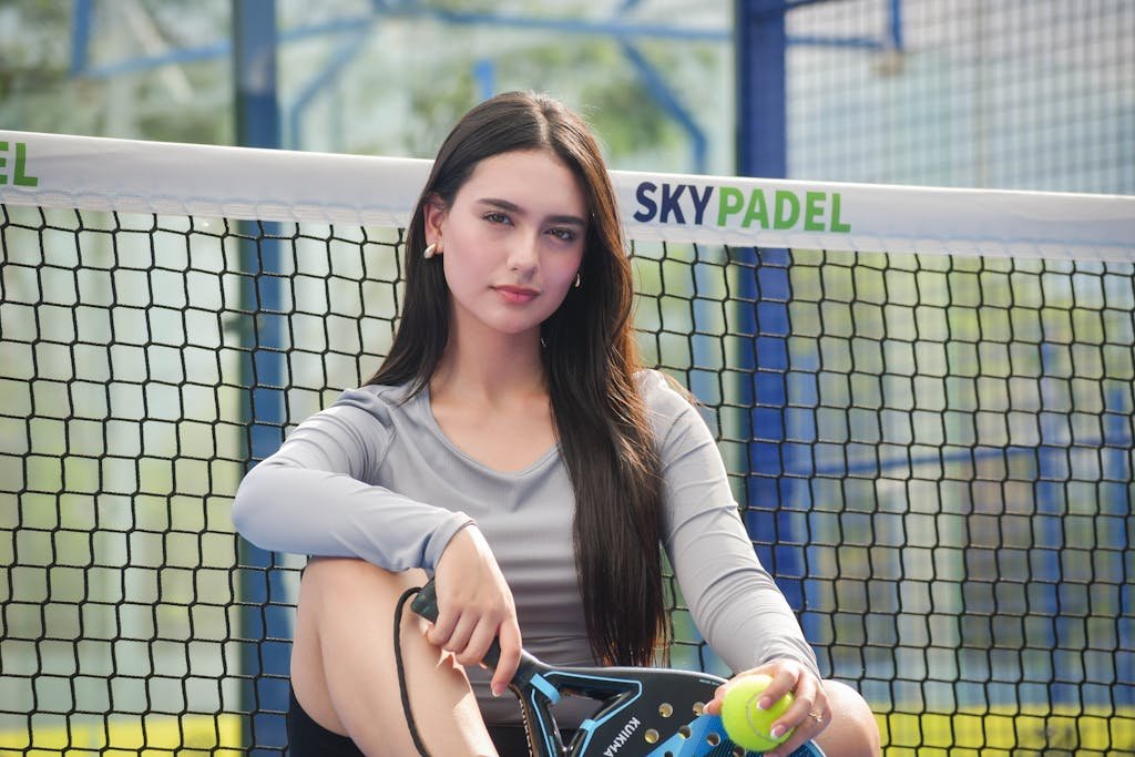 Woman Sitting with a Tennis Rocket and a Ball in her Hands